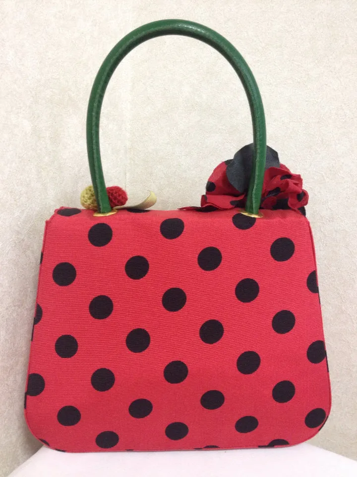 MINT. Vintage Moschino red and black canvas polkadot kelly handbag with a matching rose flower and leaf and crochet fruits motifs. 0506307